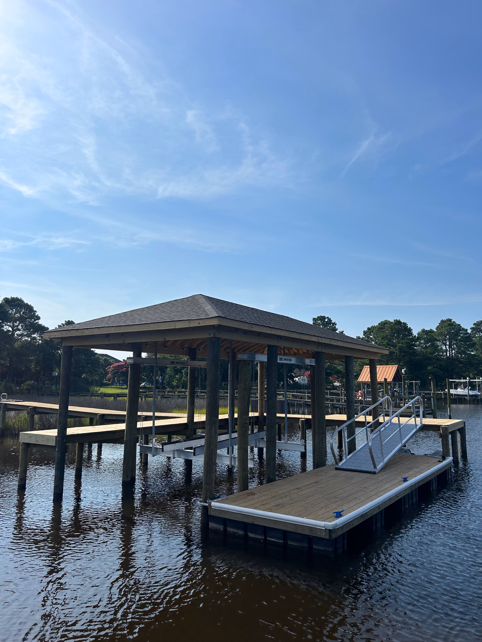 A covered boathouse with a hip roof over a boat lift and floating dock.