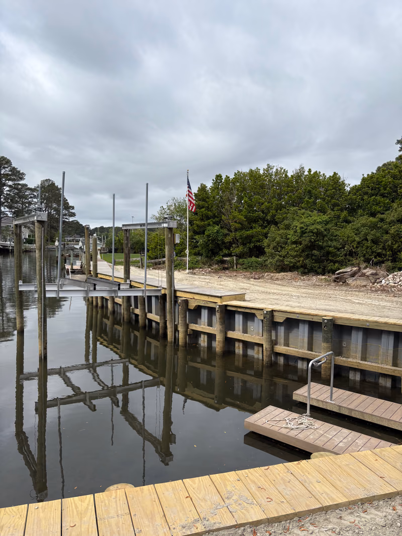A bulkhead run along a Hampton Roads creek with a flag pole on the bank.