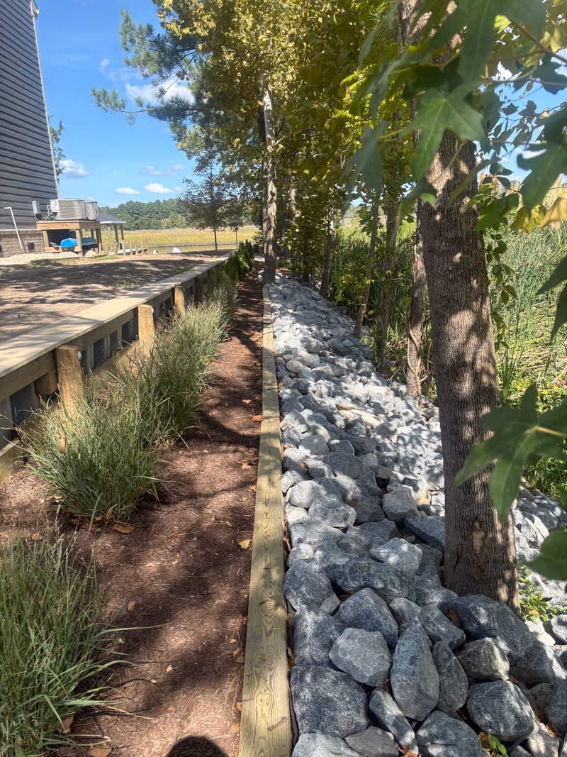 Rip rap and a low timber retaining wall with a mulched path between them.