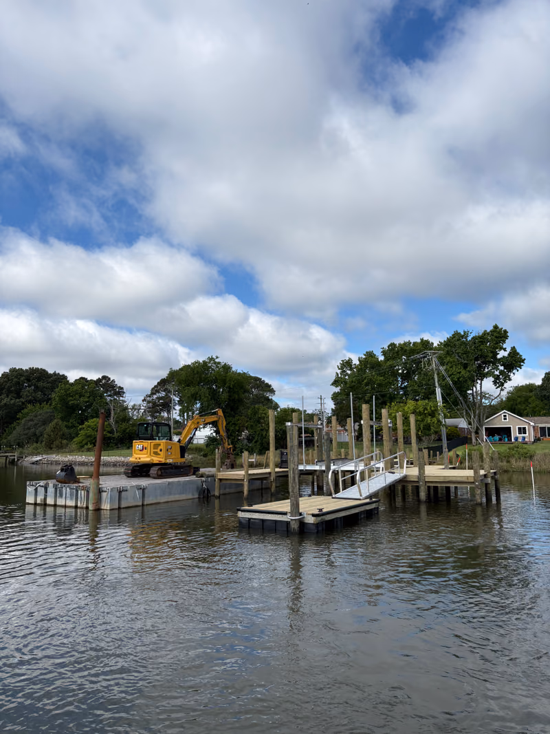 The Hanson Marine crew working a shoreline from the barge, new pilings alongside.