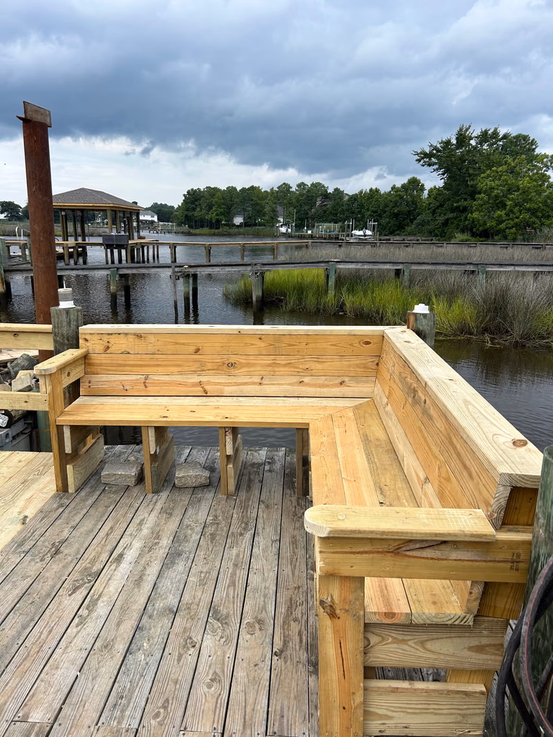 Built-in timber bench seating wrapping the corner of a dock over the marsh.