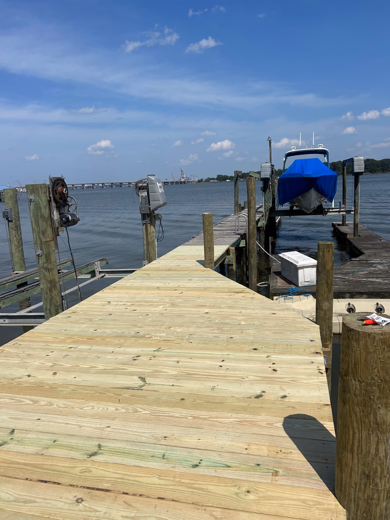 A new dock with a covered boat raised on its lift and a bridge in the distance.