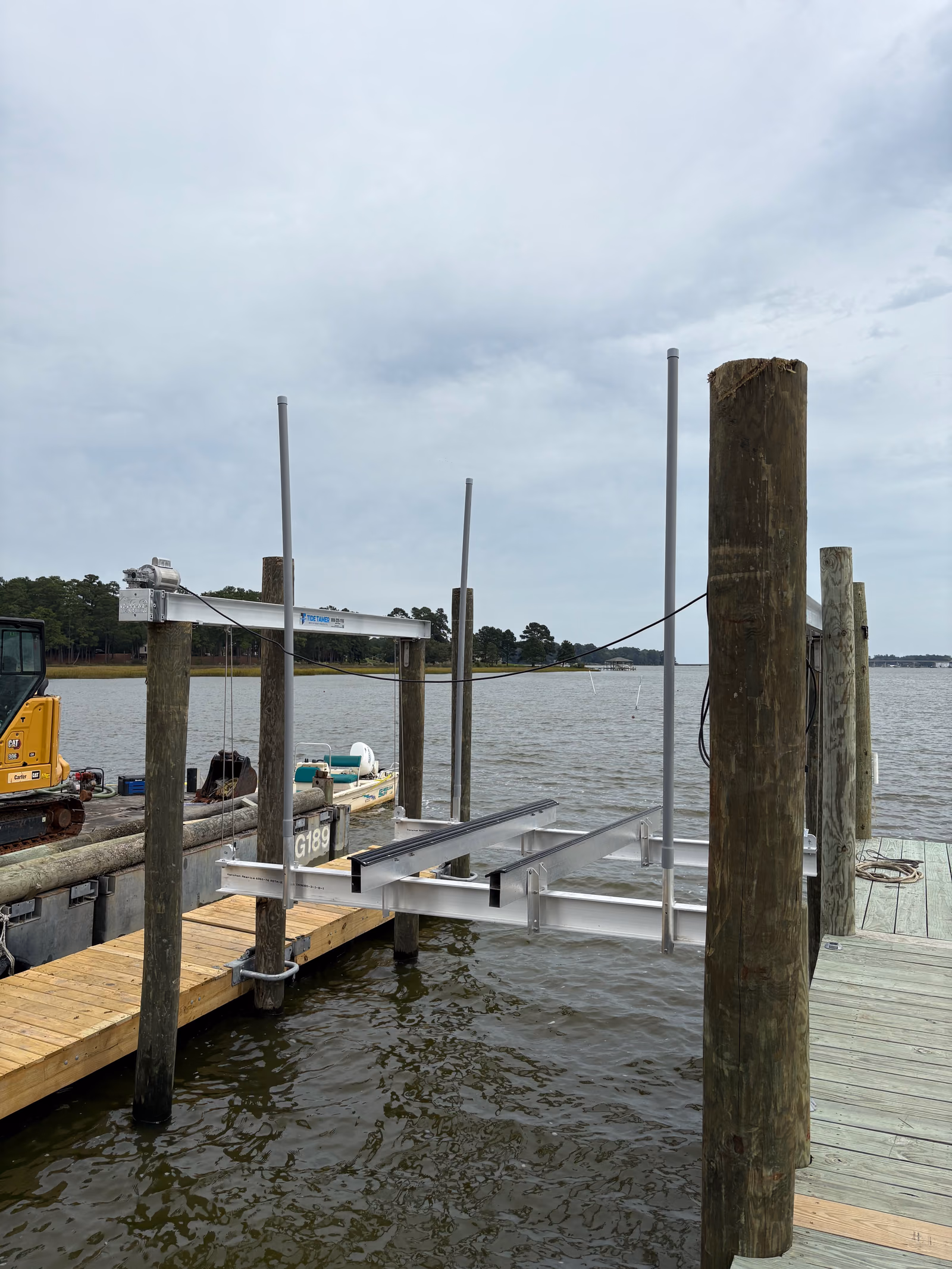 A boat lift frame set between new pilings on an overcast day, dock alongside.