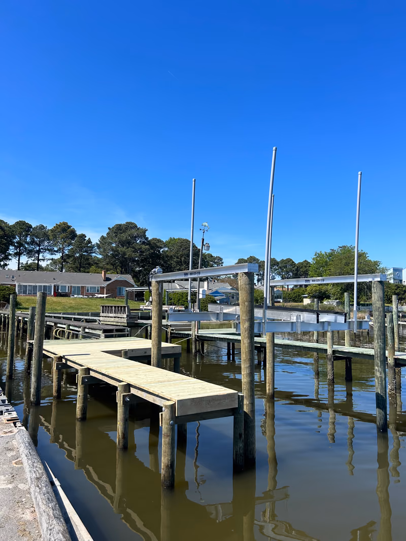 A new timber dock and two boat lift frames on a creek, houses along the far bank.