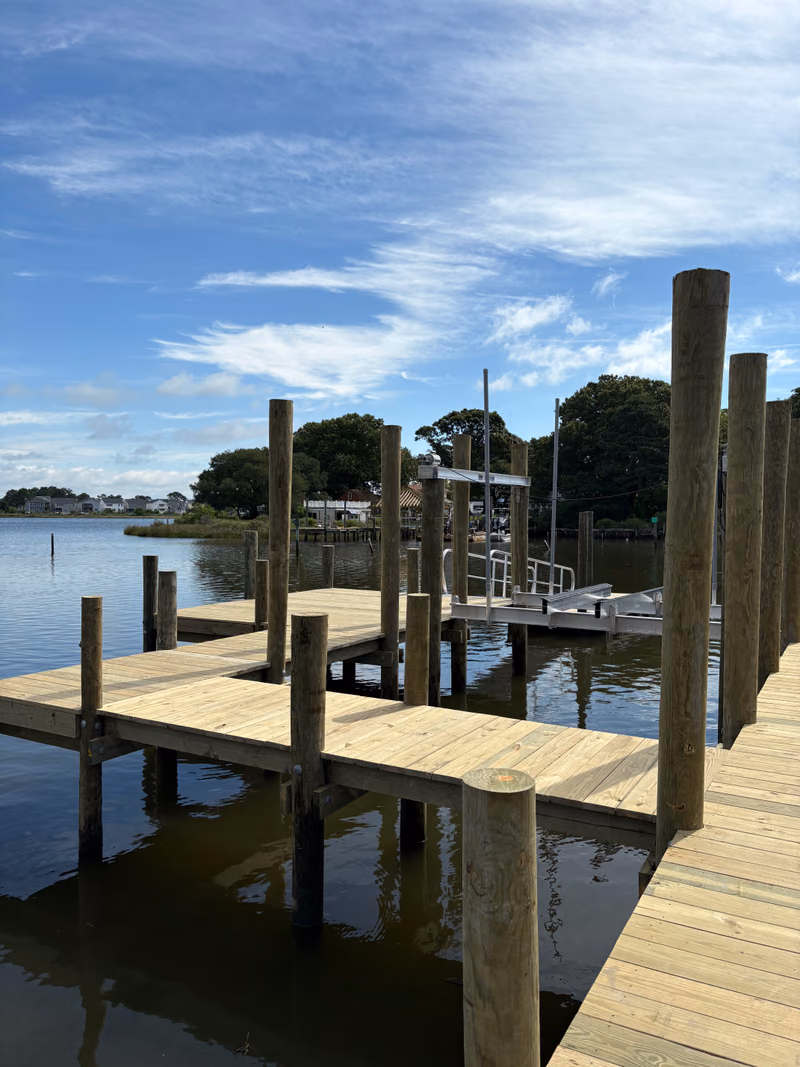 A wide timber pier with tall mooring pilings on a Hampton Roads creek.