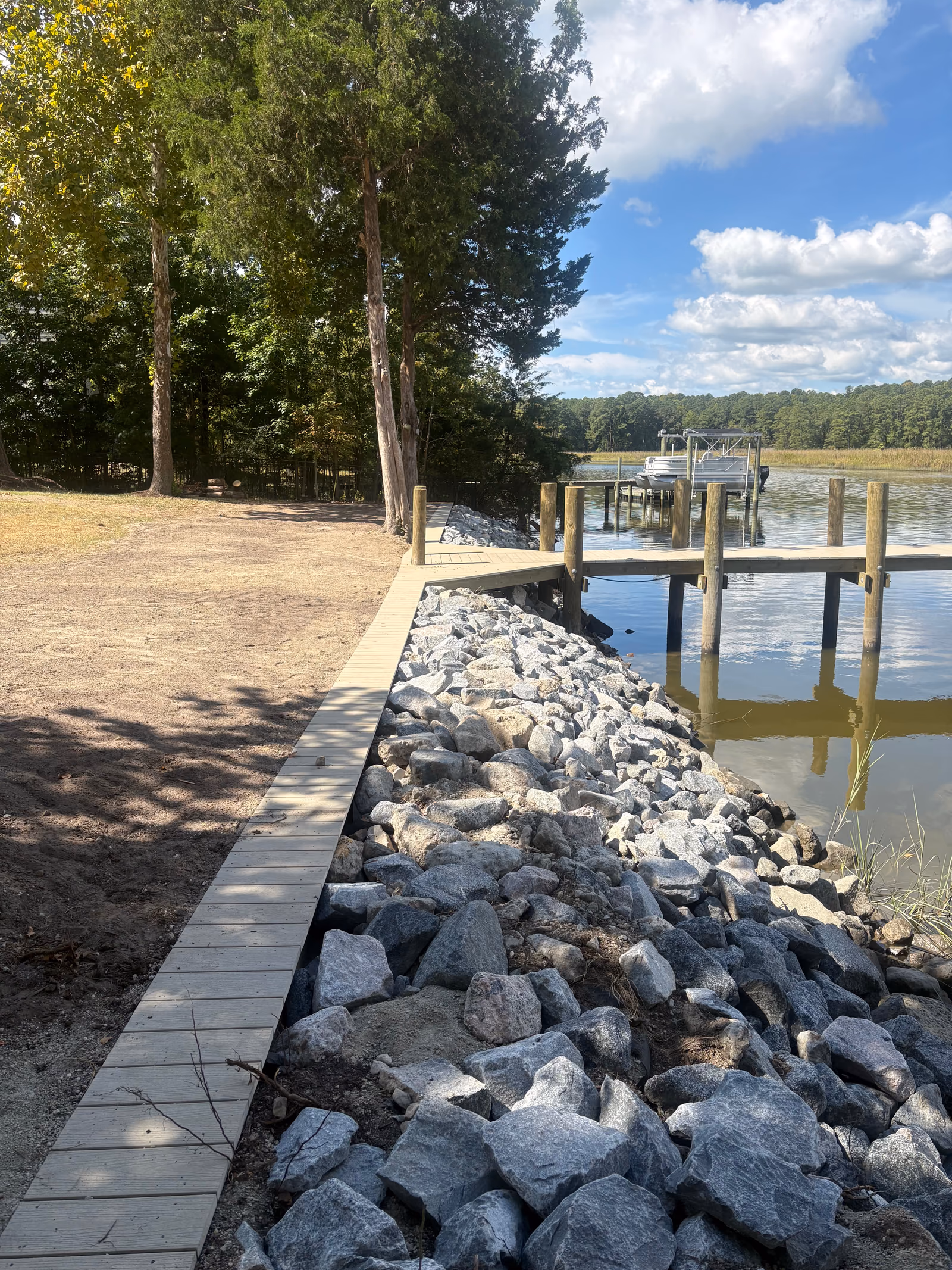 A rip rap bank with a paver path leading out to a timber dock.