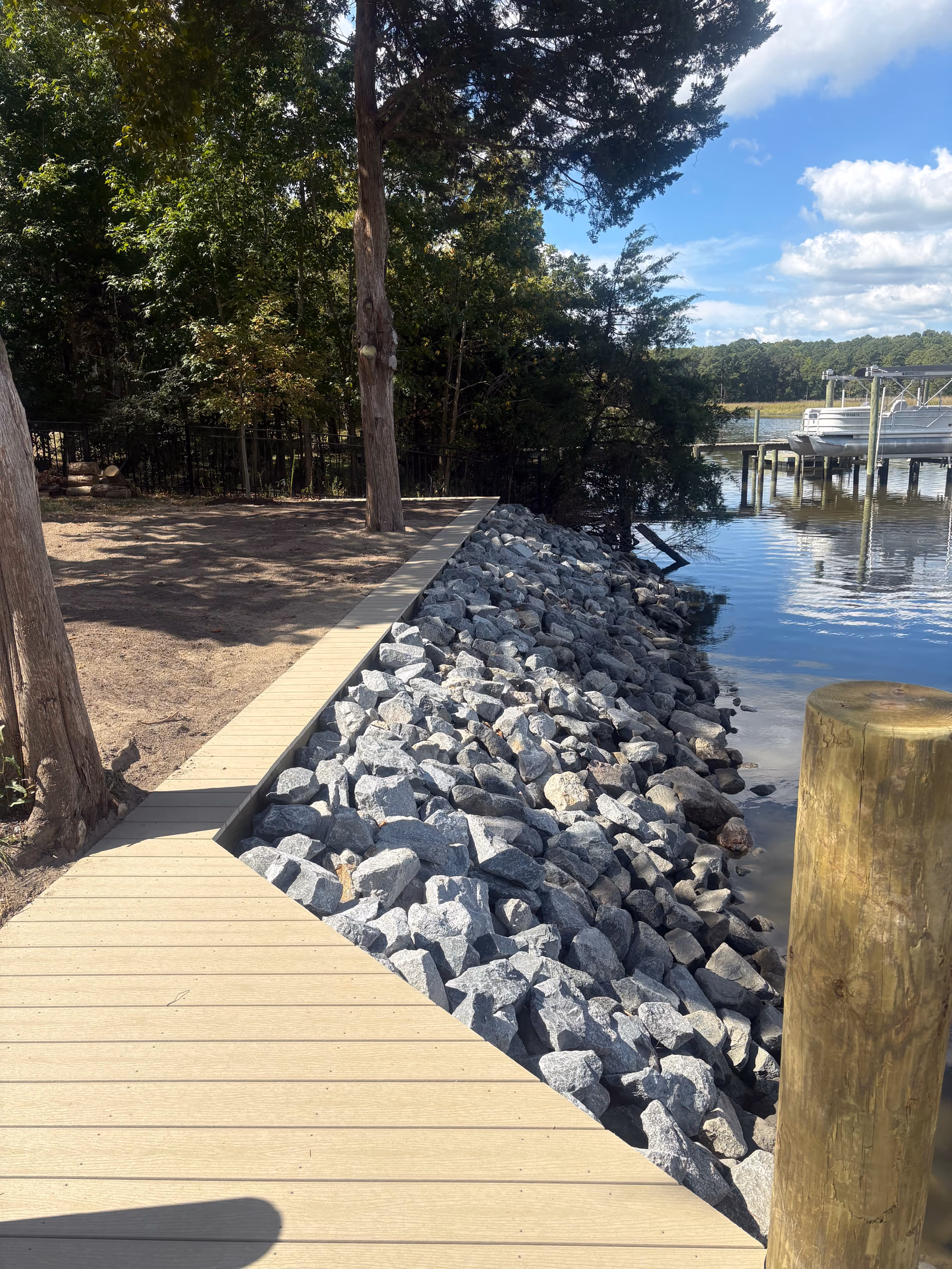 Graded armor stone placed along a shoreline beside a timber walkway.