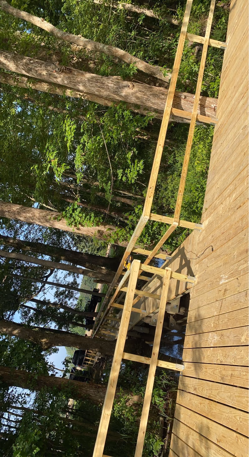 A timber walkway on low pilings running beside a rip rap bank.