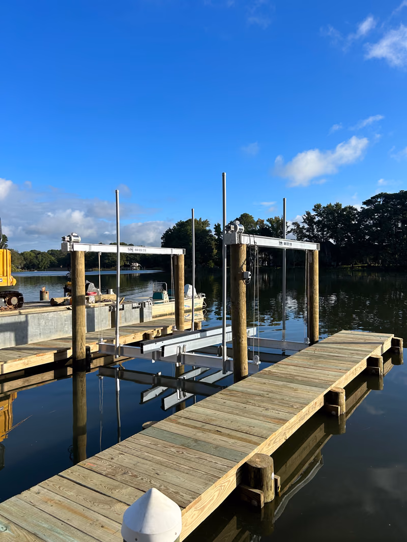 Two boat lift frames standing over the water beside a finished timber dock.